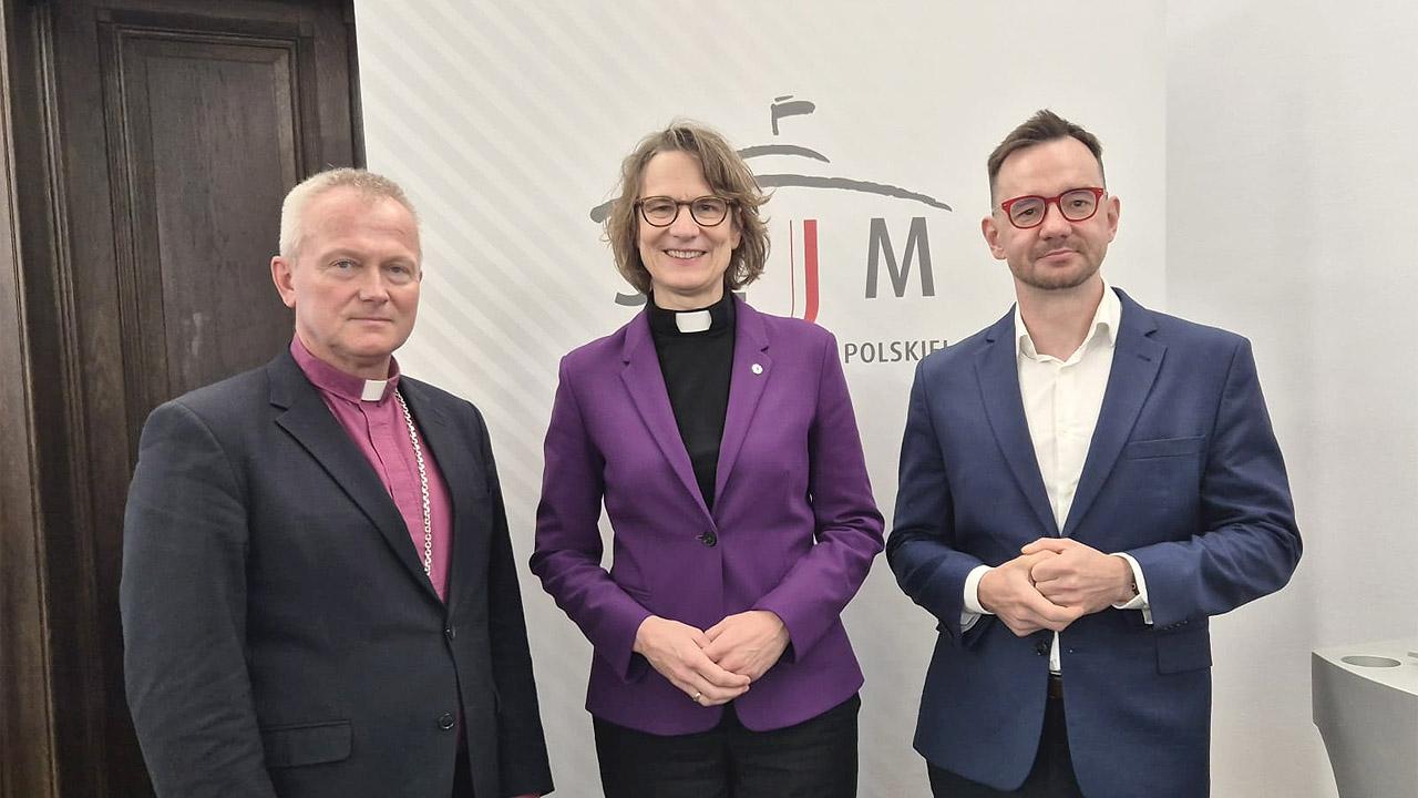 Ostdenkschrift Gruppenbild mit drei Menschen, die Kirchenpräsidentin trägt einen Kollar und einen violetten Blazer
