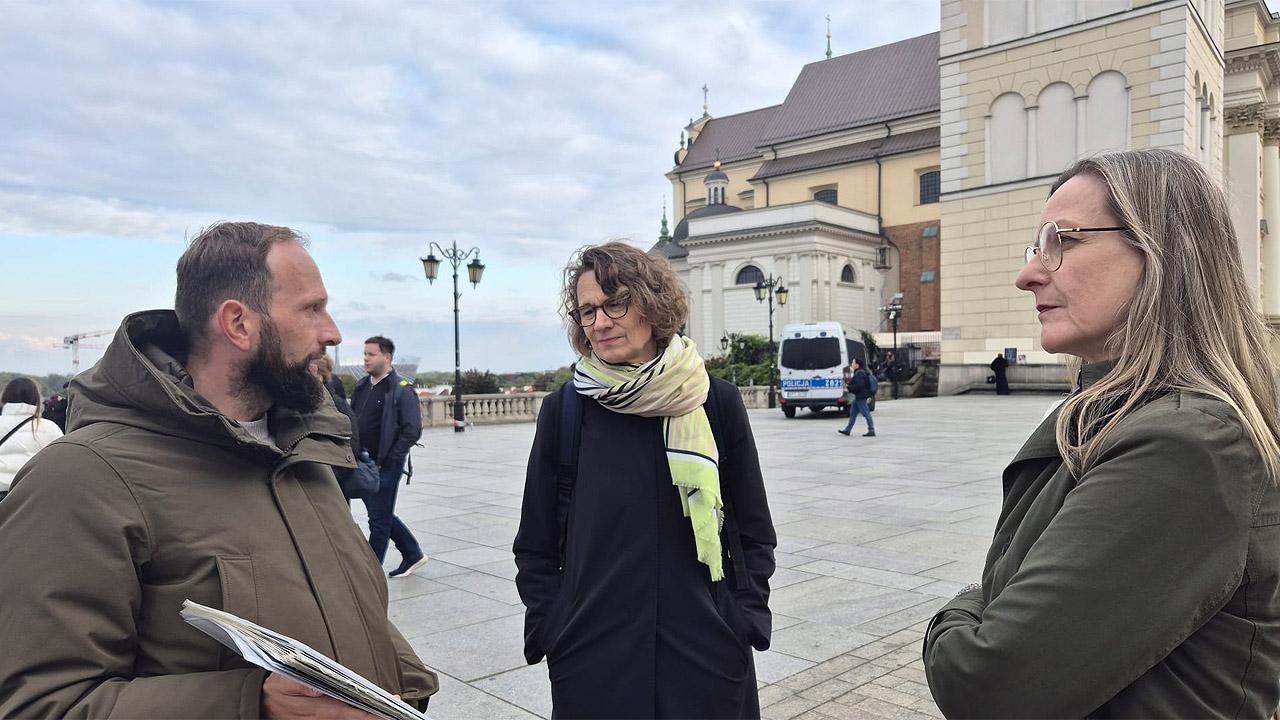 Warschau Stadführung Drei Menschen vor einer Kirche, in der Mitte Kirchenpräsidentin Tietz