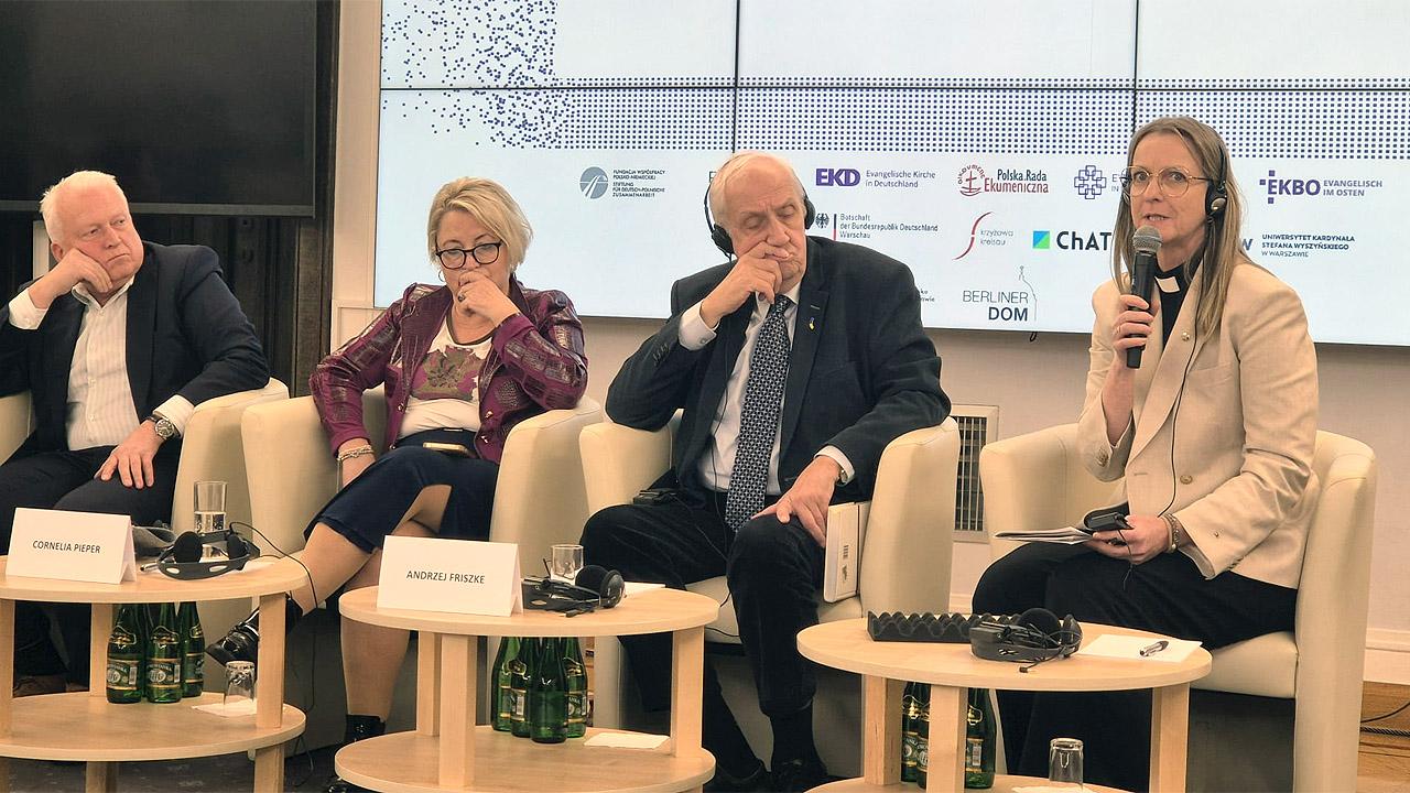 Ostdenkschrift - Talk Vier Menschen auf dem Podium, eine Frau mit Kollar hält das Mikrofon und spricht