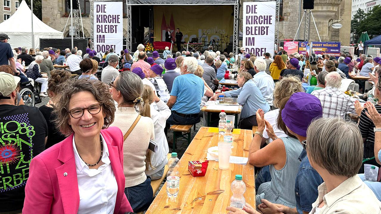 Hoffnungskulturfest Kirchenpräsidentin auf einer Bierbank, daneben viele Menschen