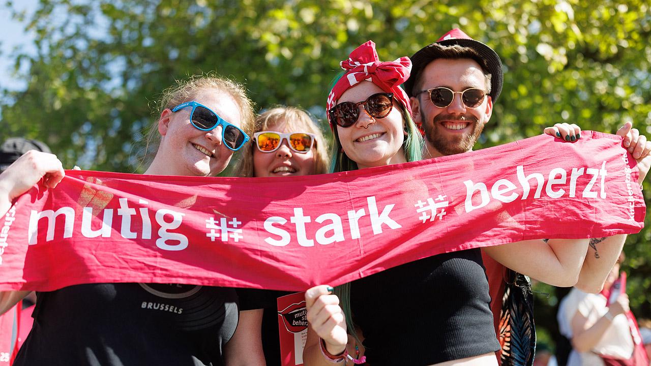 Kirchentagsmotto Mädchen halten Banner mit Worten: Mutig, stark, beherzt