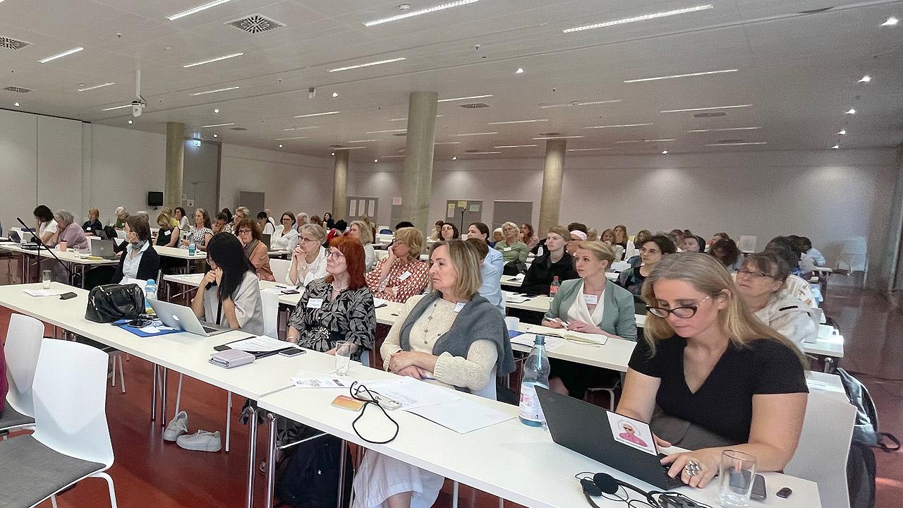Konferenz mit Frauen an langen, weißen Tischen