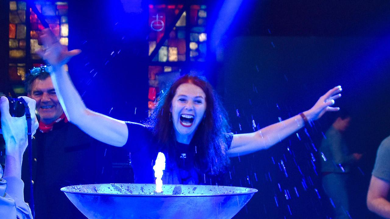 Quellenkirche Gut gelaunte Frau über kleiner Wasserfontaine in Schale, alles in bläulichem Licht