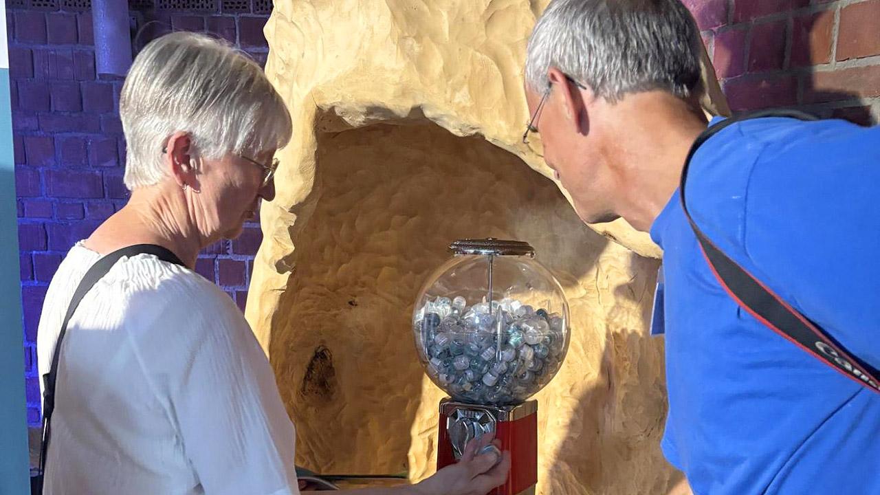 Quellenkirche Zwei Menschen vor einer Art Kaugummiautomat, in dem Segenssprüche verpackt sind