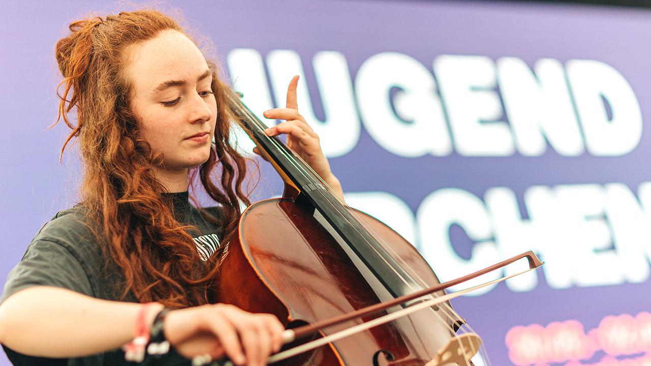 Cellospielerin Eine junge Frau mit Dreadlocks spielt Cello
