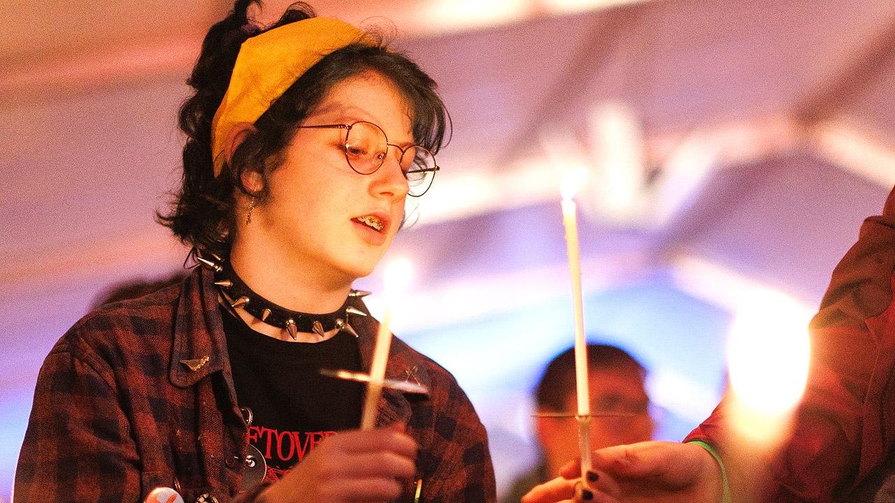 Jugendkirchentag - besinnlich Ein rockig gekleidetes Mädchen hat die Augen halb geschlossen und hält eine Kerze in der Hand