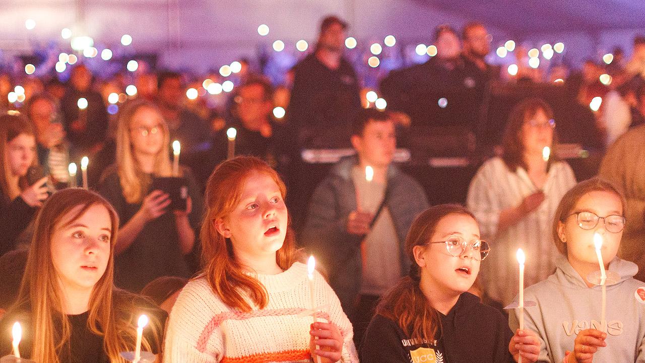 Abendandacht Viele Jugendliche halten Kerzen in der Hand bei gedimmten Licht