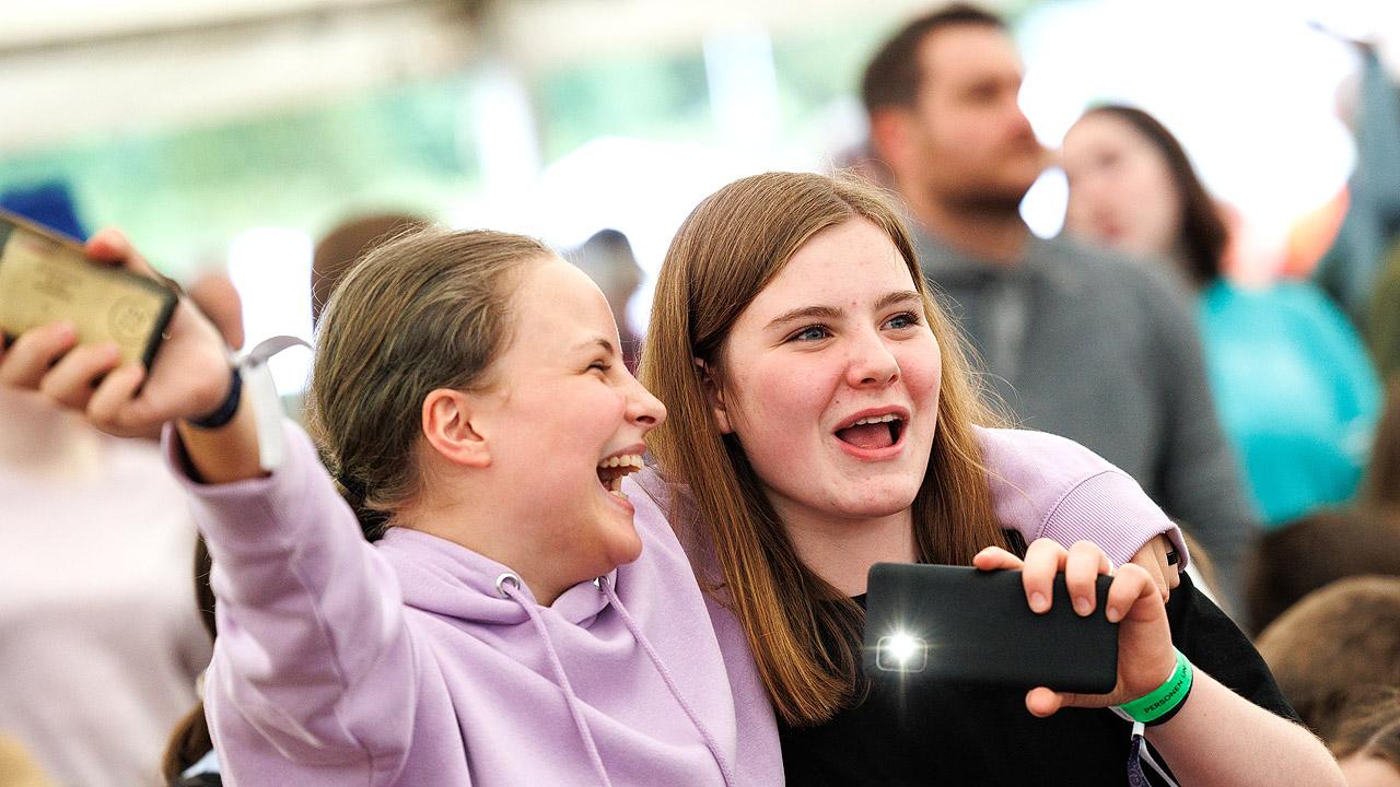 Jugendkirchentag - gute Stimmung Ein Mädchen legt den Arm um ein anderes, beide freuen sich