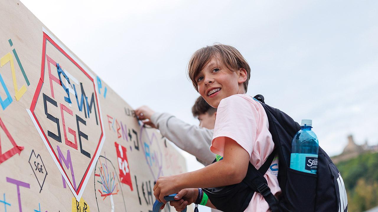 Jugendkirchentag Ein Junge ist an einem Turm hochgekletter und gestaltet dort etwas