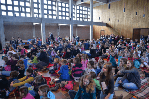 Kinder sitzen auf dem Kirchenboden udn feiern zusammen einen Familiengottesdienst